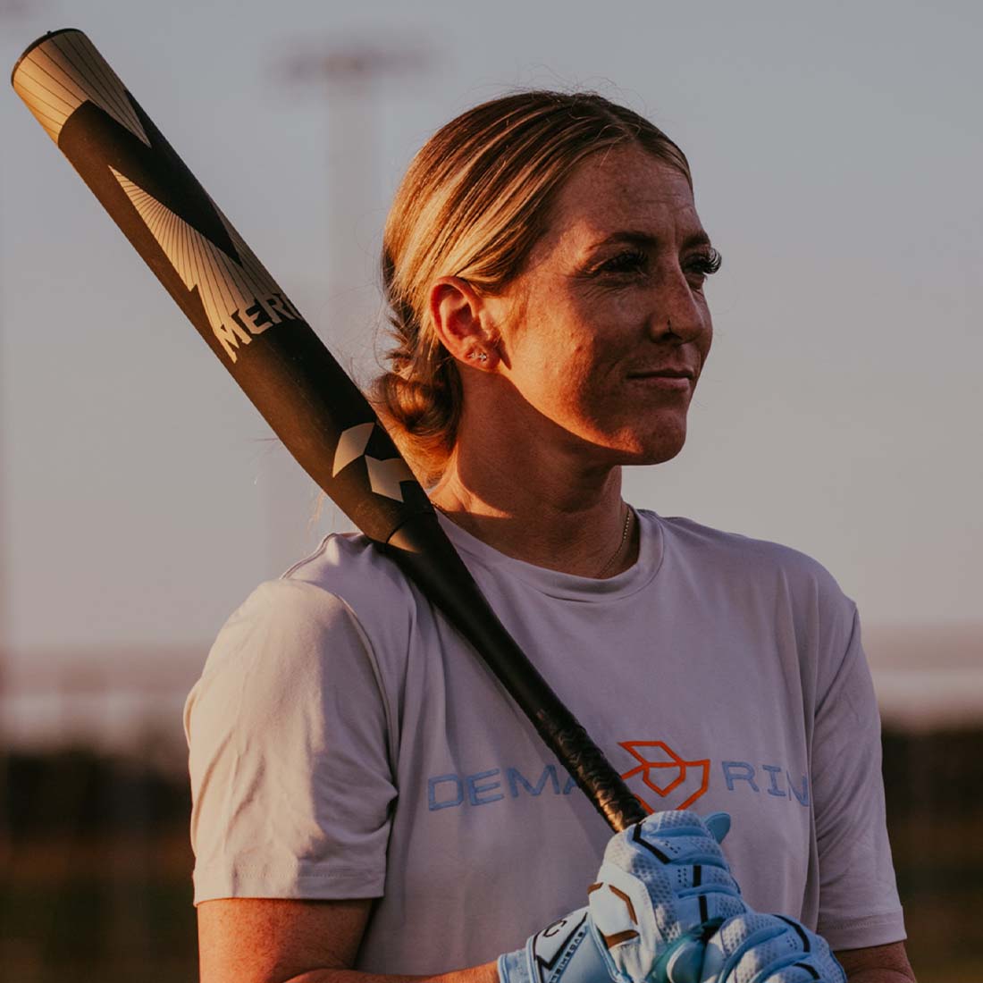 2027 DeMarini Mercy USA slowpitch softball bat 13 inch balanced Stack3d double wall composite barrel being held by a female DeMarini Pro Player