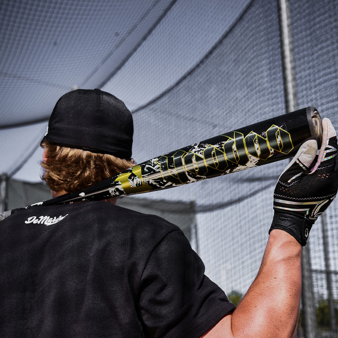 A Baseball player holding up the 2027 Voodoo One BBCOR Baseball Bat
