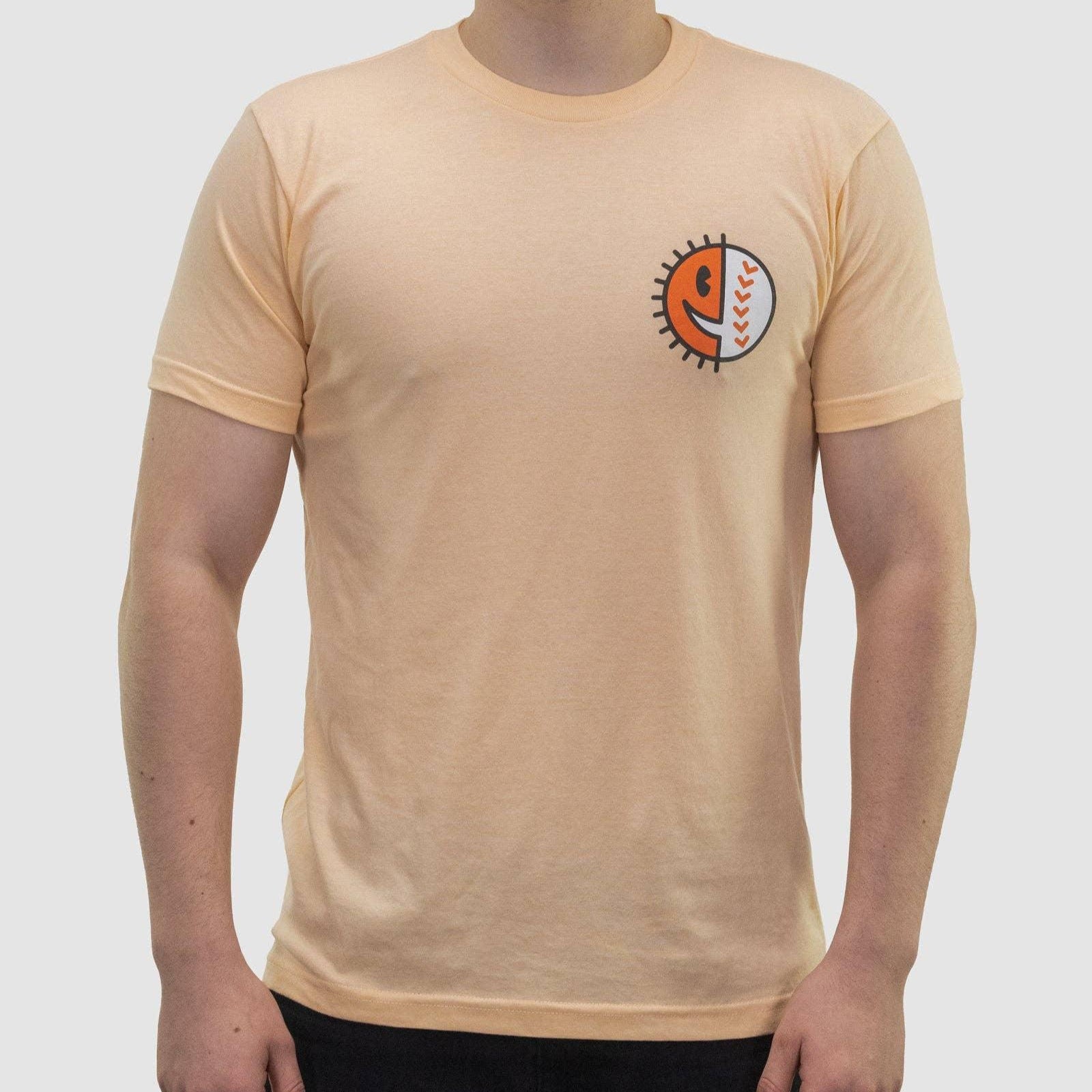A male model wearing a  peach-colored t-shirt with a graphic on the chest.