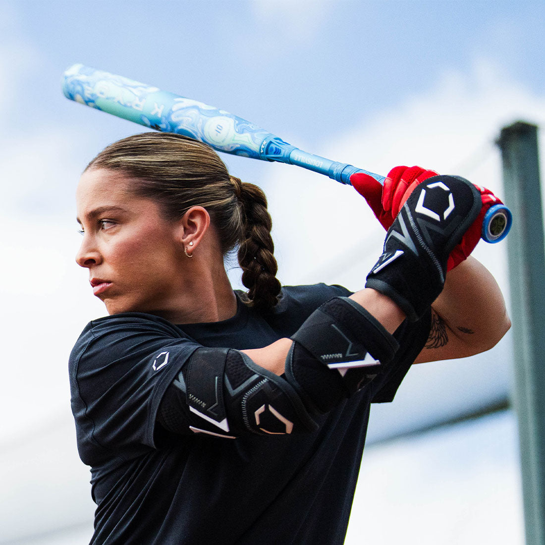 A womans softball player holding a bat wearing a black evoshield Pro-Srz 3.0 Batter's Hand Guard