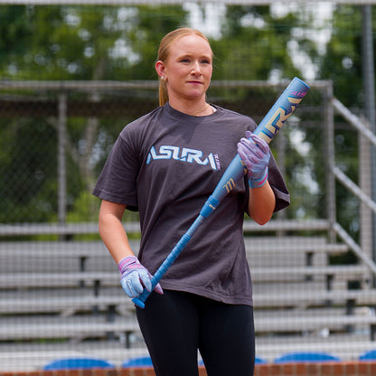 A female softball player holding the new 2027 Marucci Asura RISE Fastpitch Softball Bat on the field