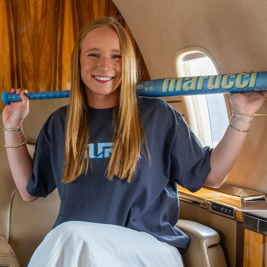 A female softball player holding the new 2027 Marucci Asura RISE Fastpitch Softball Bat inside of a Jet