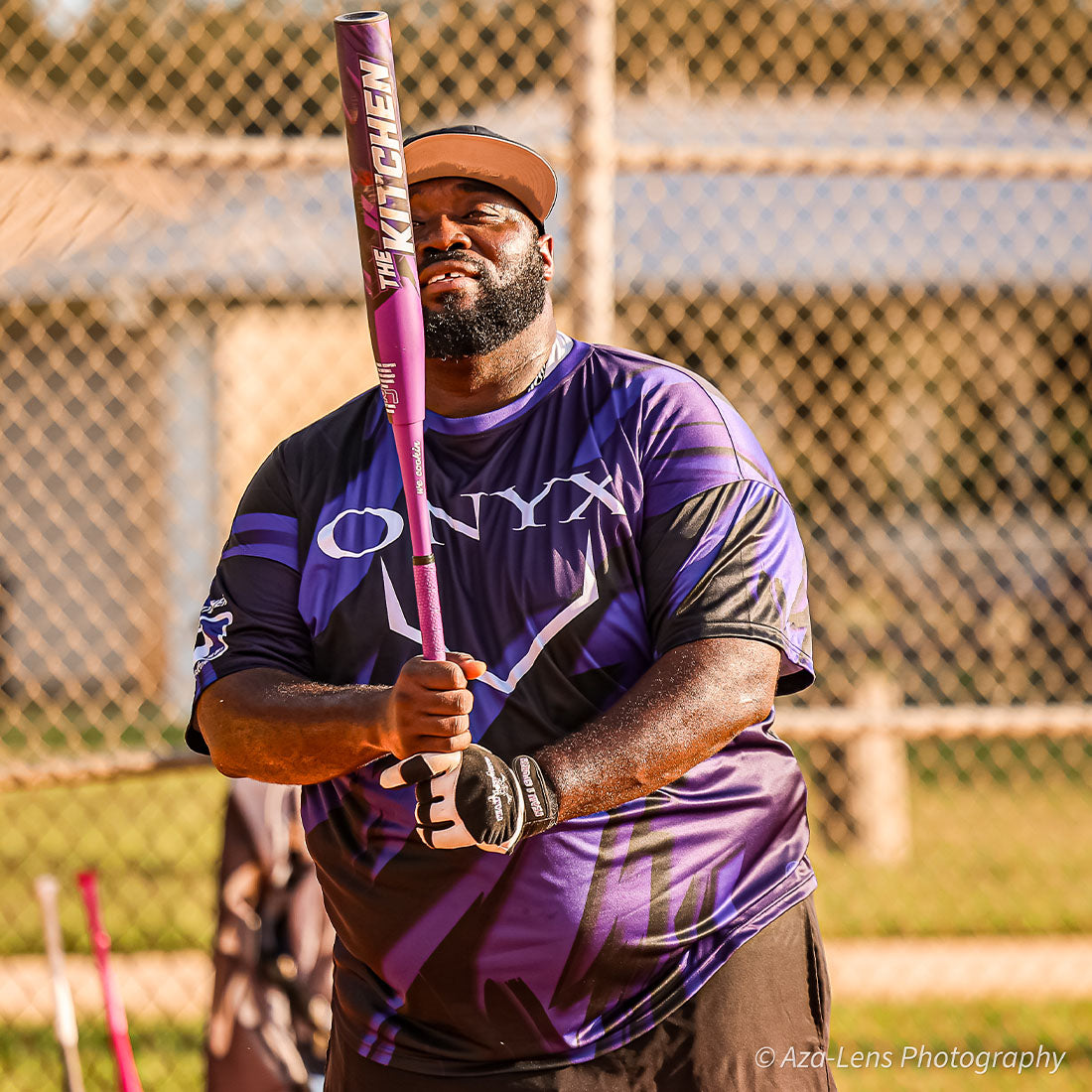 Big Chef holding his new The Kitchen Bat on a softball field.