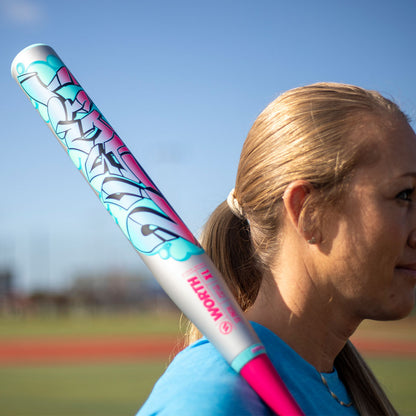 A lady holding the Worth 2 Legit XL two-piece USSSA slowpitch bat 13 inch barrel blue pink at a softball field
