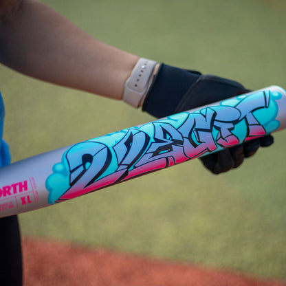 The Worth 2 Legit XL two-piece USSSA slowpitch bat 13 inch barrel blue pink being held on a softball field near dirt